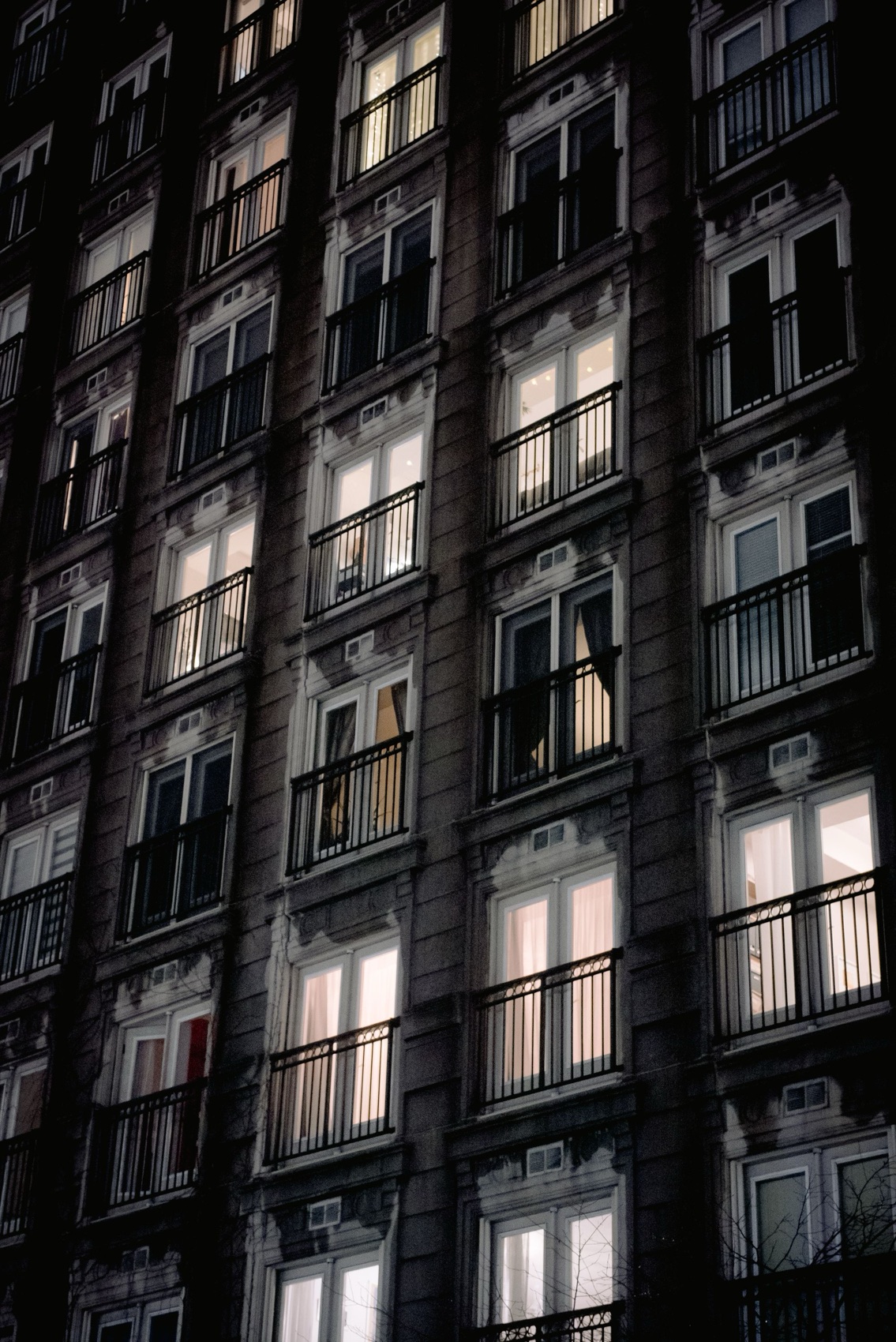 Apartment façade at night, windows glowing warm